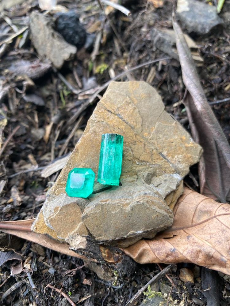 Esmeralda tallada y cristal en bruto sobre la roca