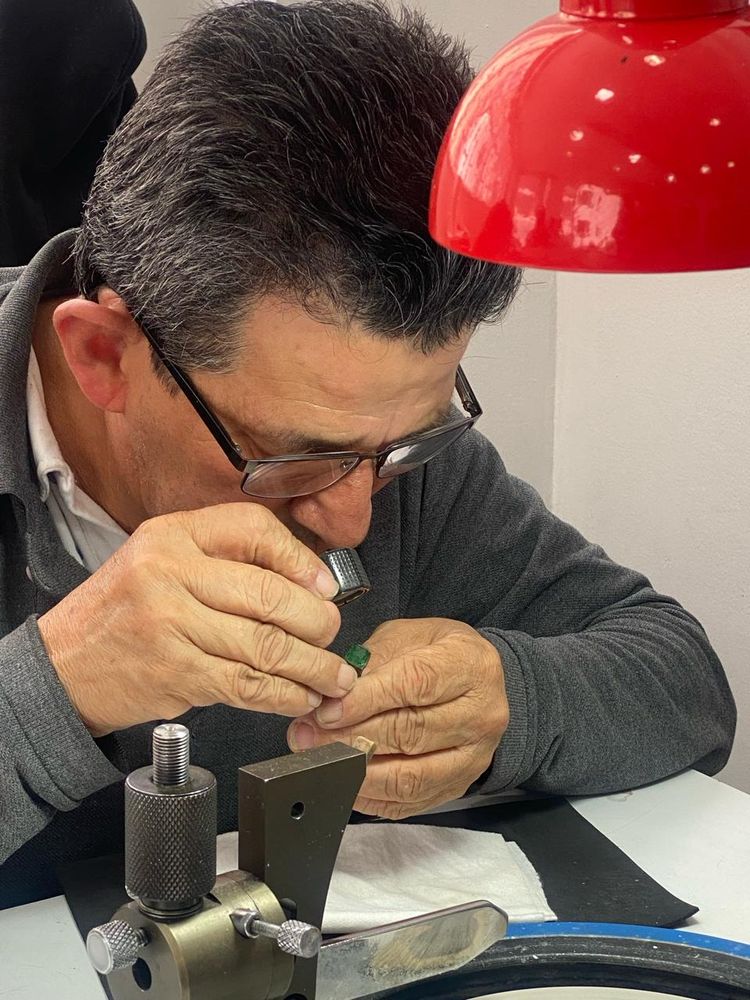 Gemólogo evaluando una esmeralda con lupa bajo la lámpara
